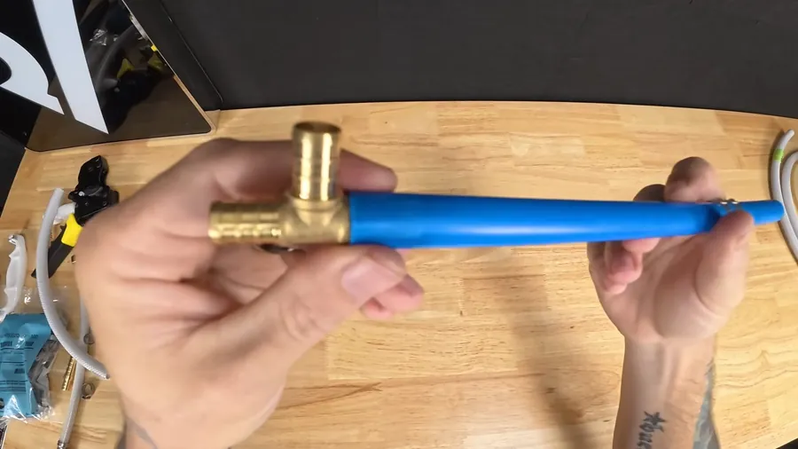 Blue flexible PEX pipe and brass fitting in hand for Galvanized Pipe vs. PEX: What Lakewood Homeowners Are Choosing When They