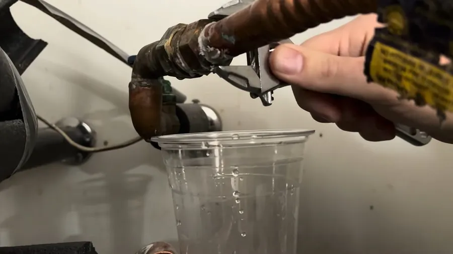Copper water heater inlet connection dripping into a glass for Signs Your Galvanized Pipes Are Failing: A Lakewood Homeowner’s Guide