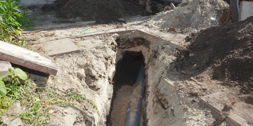 Exposed pipe trench beside a driveway and walkway for Plumber in Artesia, CA