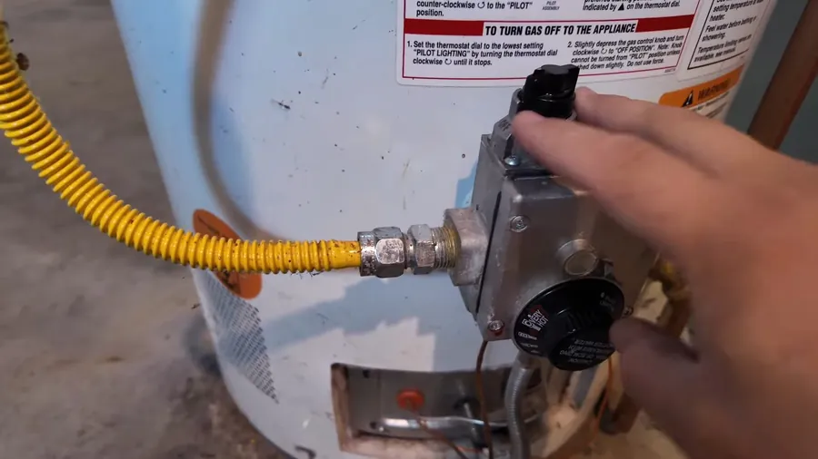 Hand tightening a gas shutoff connection beside a water heater for Gas Line Repair & Installation in Lakewood, CA