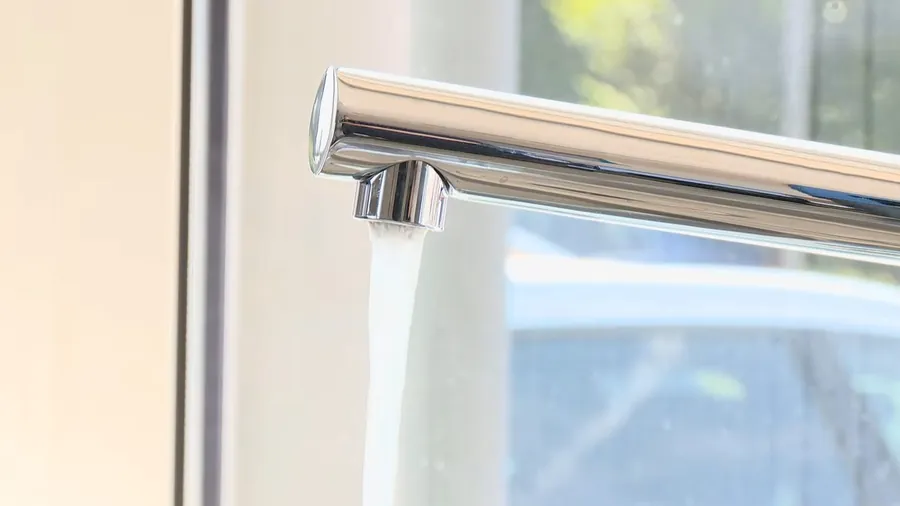 Modern kitchen faucet running water into a sink for Faucet Repair & Replacement in Lakewood, CA