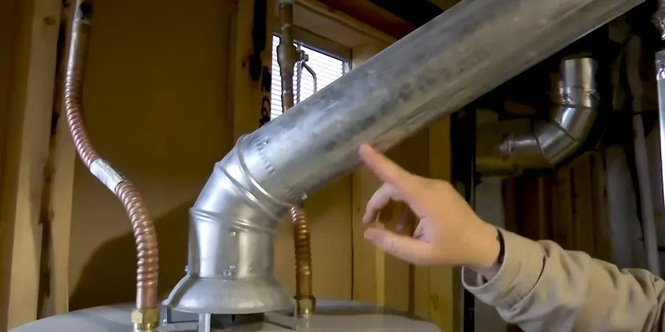 Plumber pointing to water heater vent and piping for Water Heater Repair in Lakewood, CA