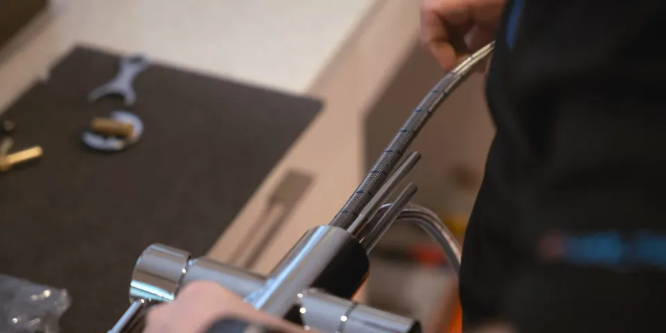 Plumber tightening a faucet connection with a wrench for Faucet Repair & Replacement in Lakewood, CA