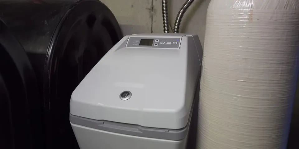 White water softener cabinet beside a brine tank for Water Softener Installation in Lakewood, CA